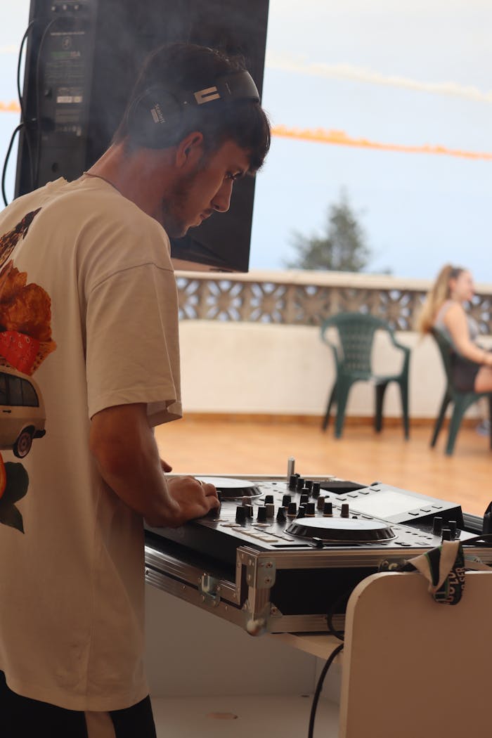 About A young male DJ mixing music at an outdoor summer event, creating a lively atmosphere.