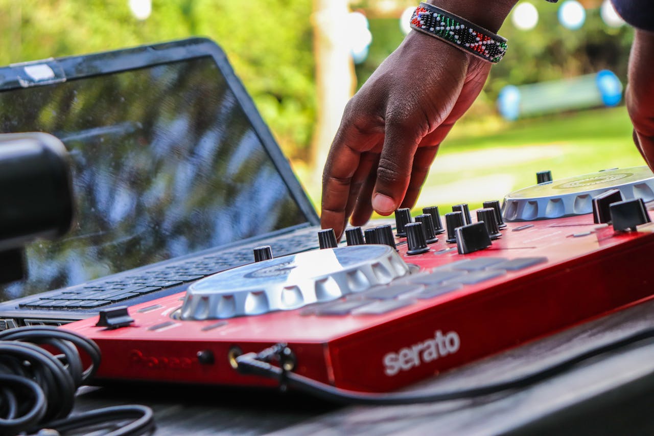 Close-up of a DJ adjusting a red mixer outdoors in Nairobi, Kenya.
