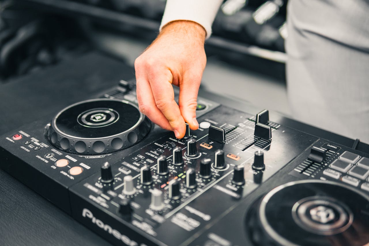 Close-up of a DJ's hand adjusting a mixer at a live music event, showcasing professional sound equipment.